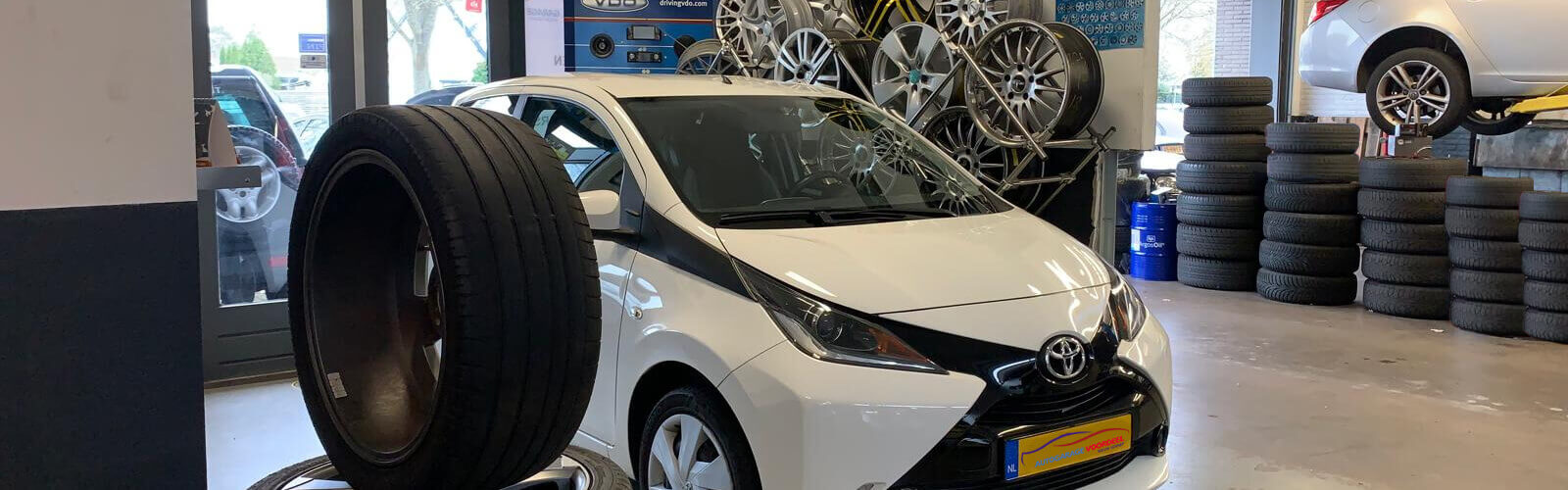Showroom van Autogarage Voordeel met een Toyota Aygo, velgen en stapels banden