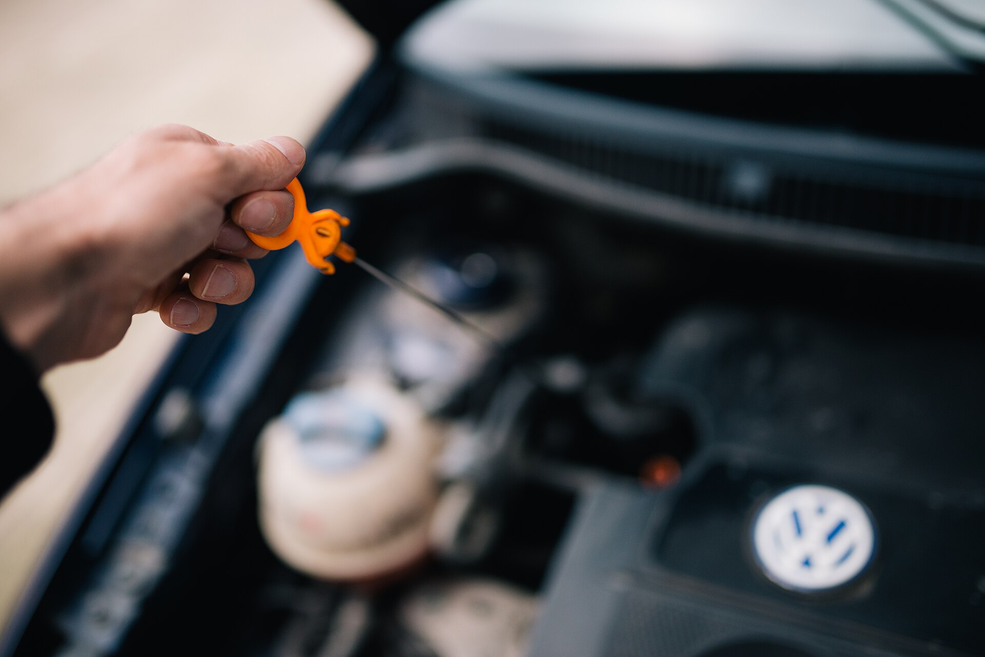 Hand trekt de oliepeilstok uit een motor om het oliepeil te controleren