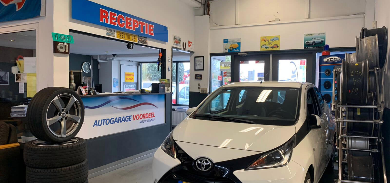 De receptie van Autogarage Voordeel met een Toyota Aygo en banden in de werkplaats